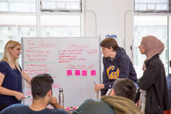 Students discussing social problems in class in front of a whiteboard